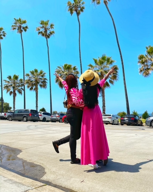 Two women in La Jolla californa looking ahead at palm trees with arms outstretched