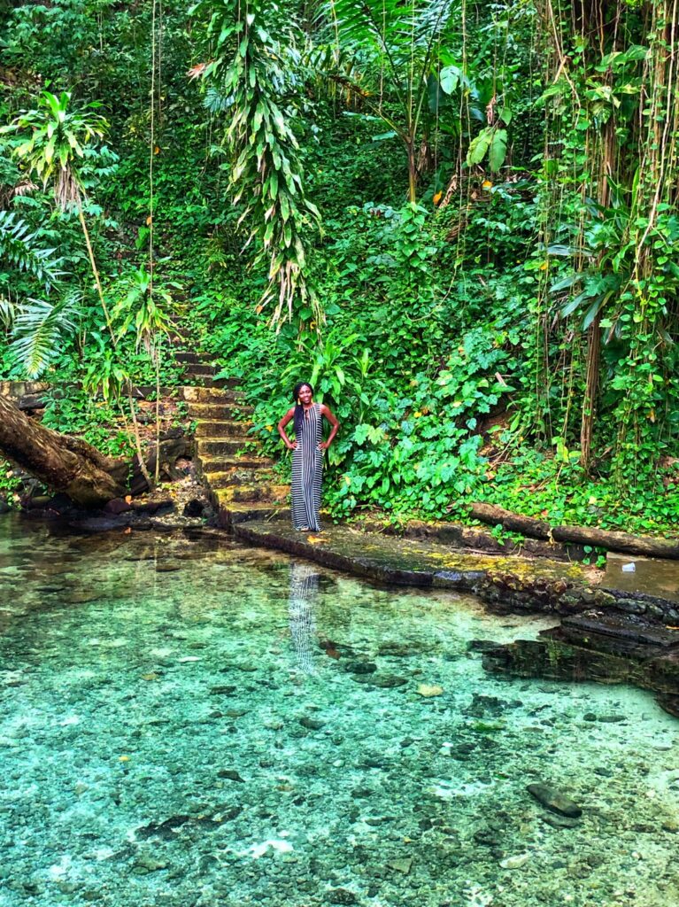 Woman at Blue Lagoon standing in lush vegetation near blue waters
