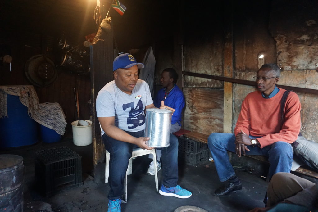 Chipa, our guide showing us how to drink Umqombothi, african beer in the Shebeen