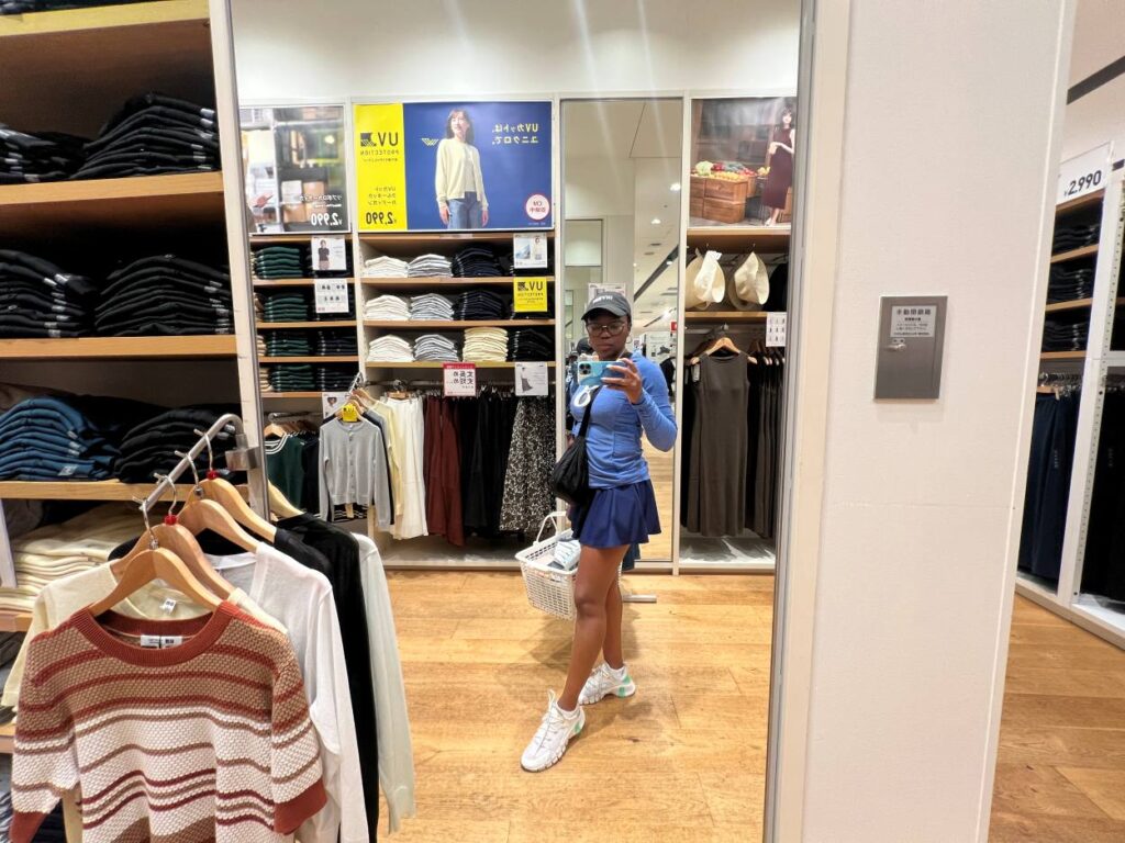 Woman browsing T-shirts in Uniqlo Japan, a top place to buy casual souvenirs and apparel.