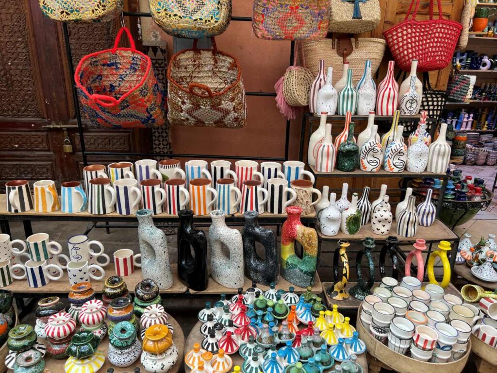 Display of traditional Moroccan ceramics in Marrakech featuring colorful tagines, spice jars, pitchers, and intricately patterned cooking pots.