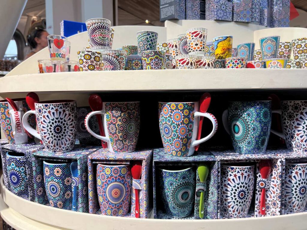 helves stacked with Moroccan ceramic kitchenware in Marrakech, showcasing detailed geometric designs on cookware, serving pieces, and decorative jars.