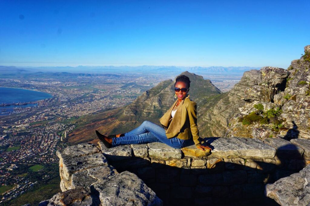 A woman sitting atop Table Mountain in Cape Town, celebrating adventurous and scenic 40th birthday trip ideas
