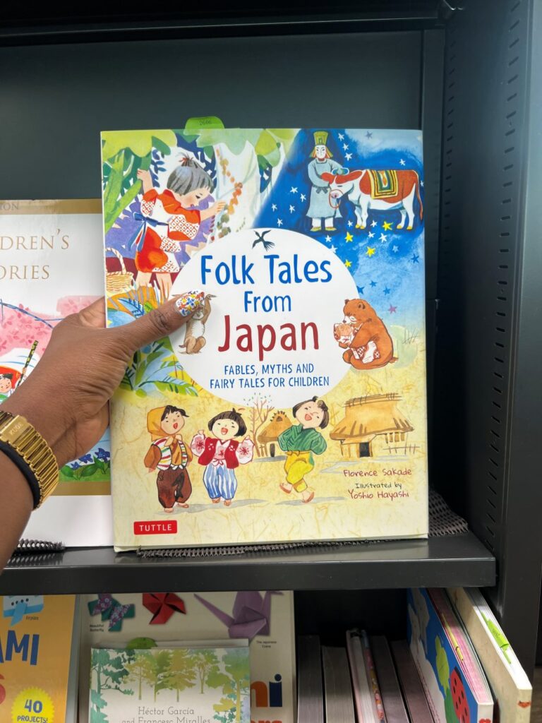 A travel blogger picking a Japanese folk tale book as a souvenir before leaving Japan